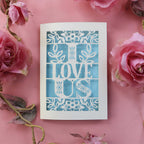 A papercut love Valentine's card with the words 'I LOVE US' cut out.