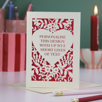 Card with red and cream floral heart design and text on a table with stationery items.