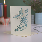 3D Butterfly Greeting card with push-out butterfly wings and floral design on a table with a candle and vase in the background
