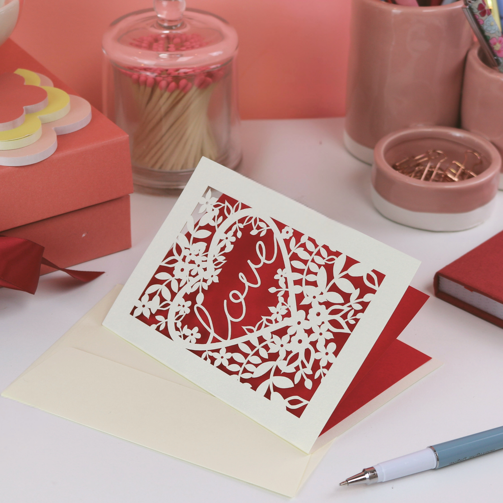 Decorative Valentine's card with floral design and 'Love' text on a desk with stationery items.