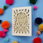 Laser cut Mom Card with 'Merry Christmas to my Mom' text surrounded by colourful pom-poms on a blue background