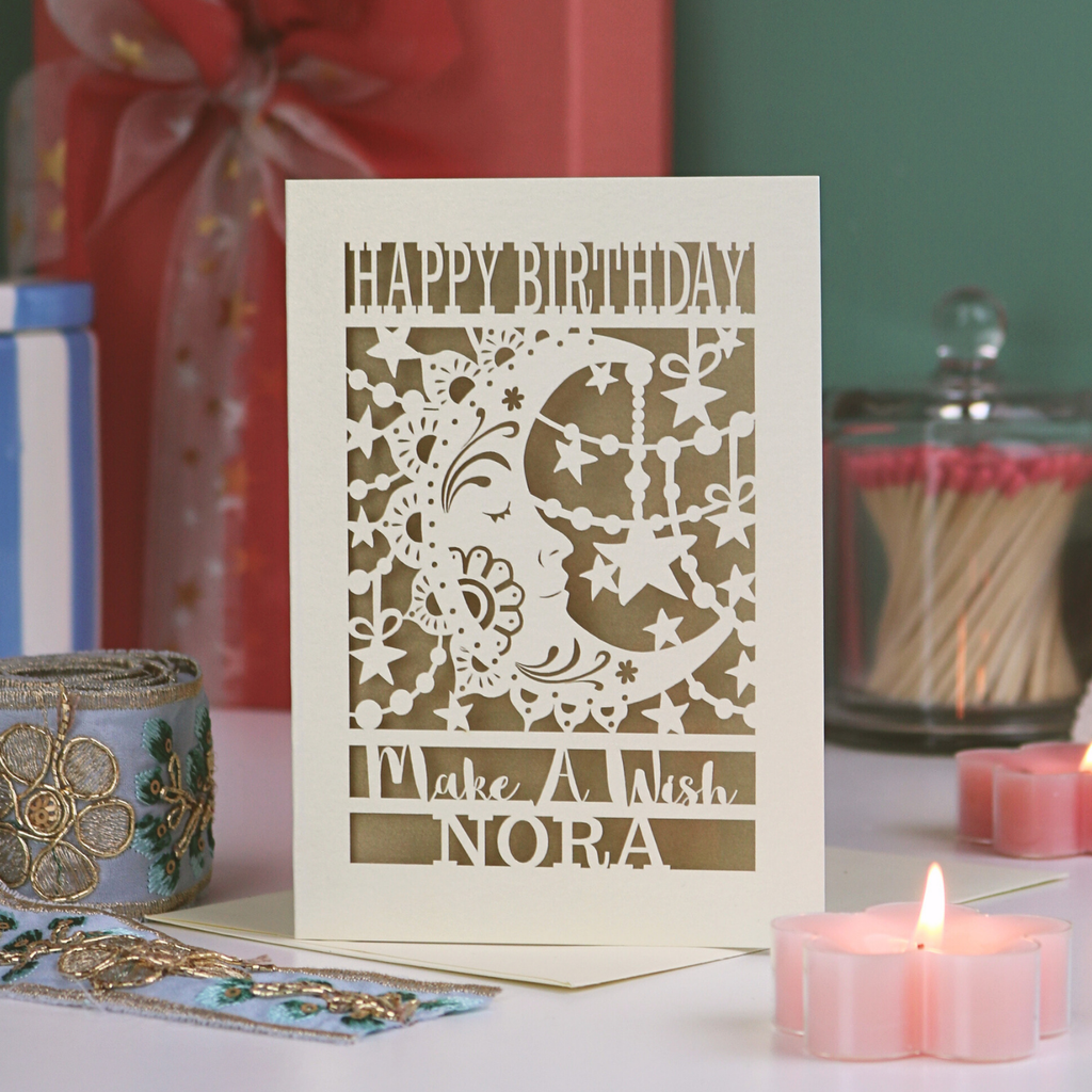 Personalized birthday card with decorative elements on a table with candles and gifts.