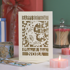 Personalized birthday card with decorative elements on a table with candles and gifts.
