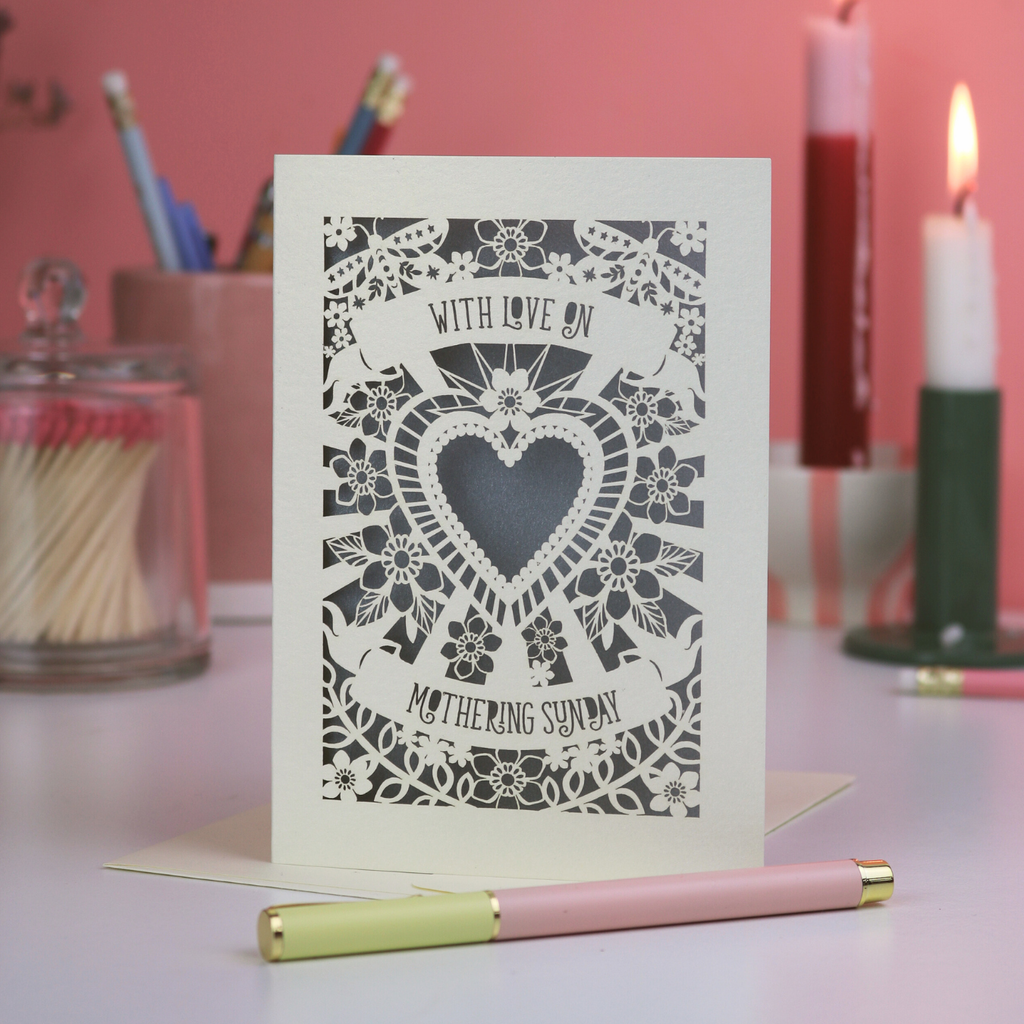 Laser Cut Mothering Sunday Card with decorative heart design and text on a table with stationery items.
