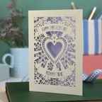Card with floral design and 'Happy Mother's Day' text on a green surface with stationery items.