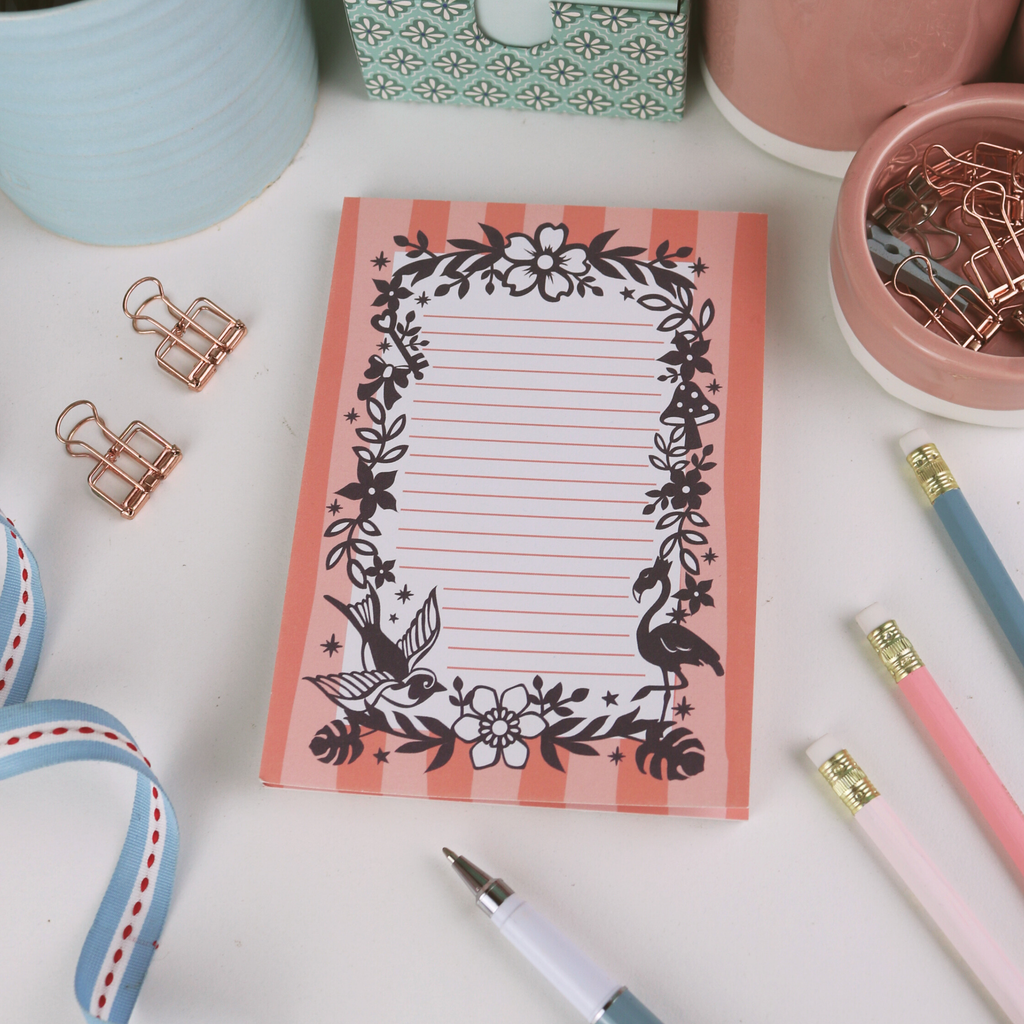 Notepad with decorative border on a desk with stationery items