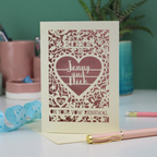 Personalized vow renewal card with decorative heart design on a table with stationery items.