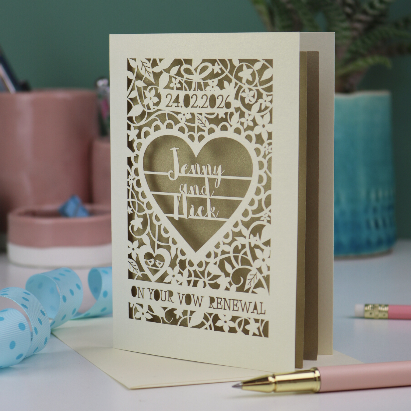 Personalized cut out vow renewal card with decorative patterns and text on a table.