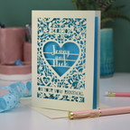 Personalized vow renewal card with decorative heart design on a table with stationery items.