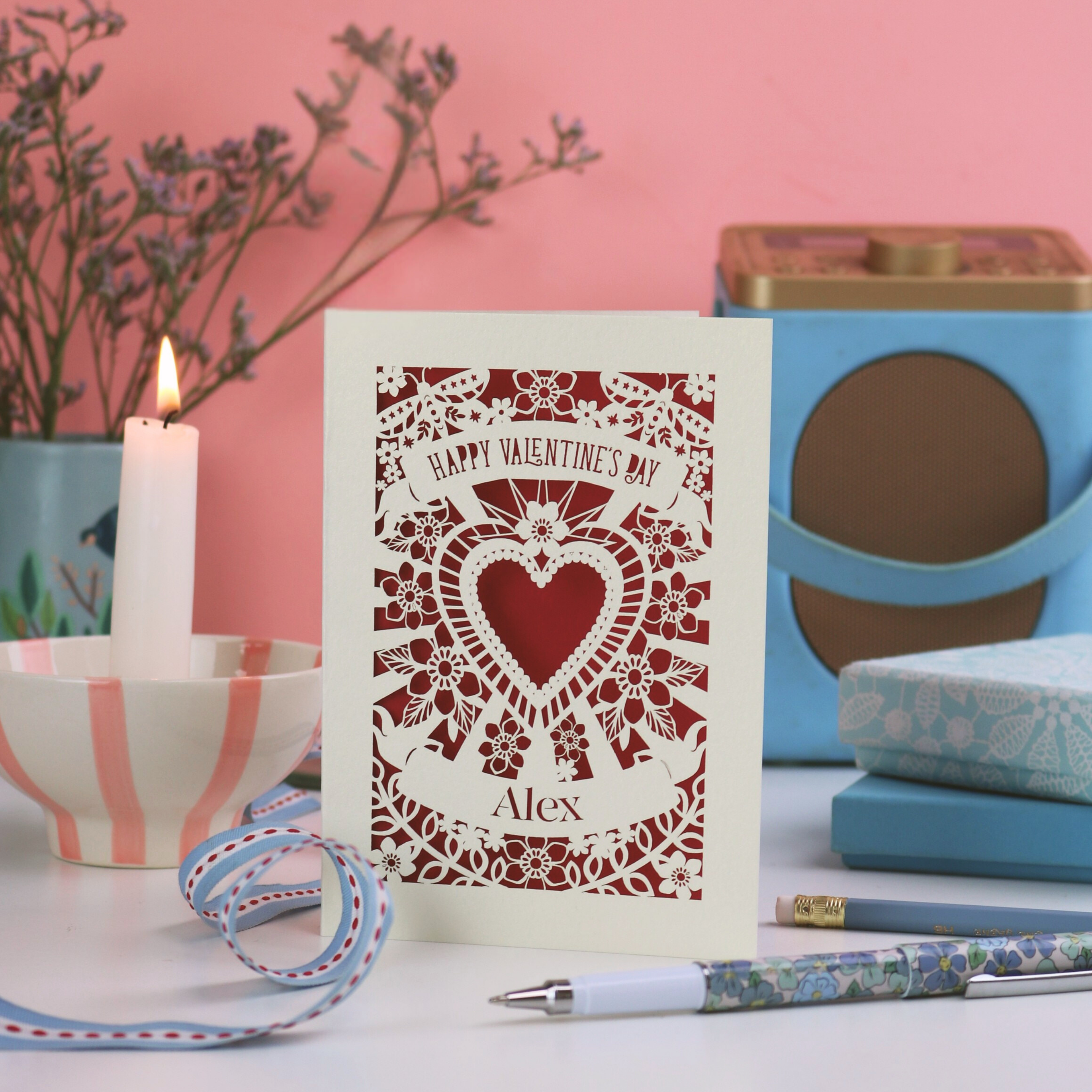 Personalised Valentine's Day card with a laser cut heart design on a table with decorative items.