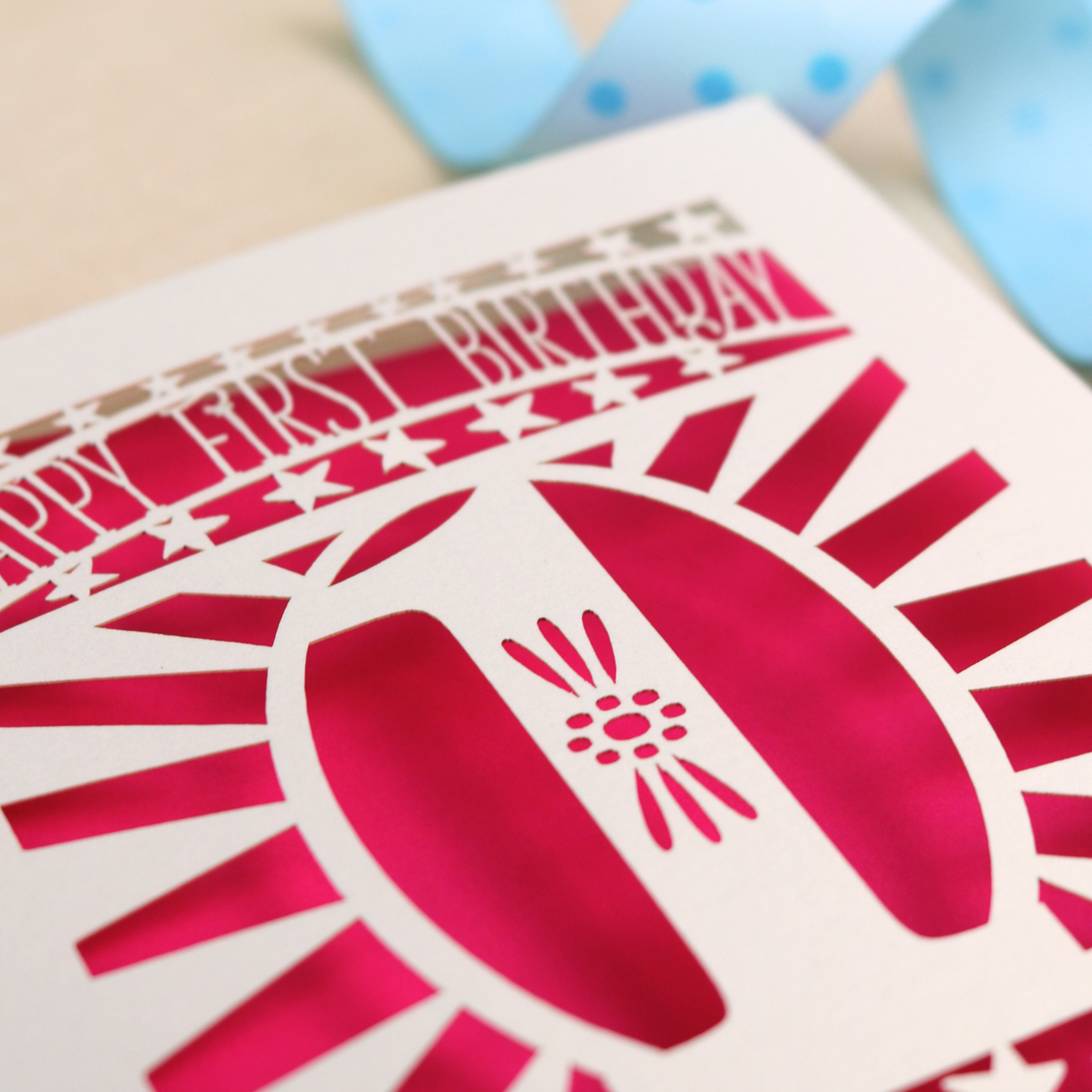 Close up detail of a Personalised Baby's First Birthday card, laser cut with star borders and "Happy First Birthday" at the top and a decorative cut out number 1 in the centre 