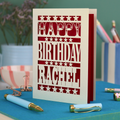 A laser cut personalised birthday card that says "Happy Birthday Rachel" in bold text with star design.