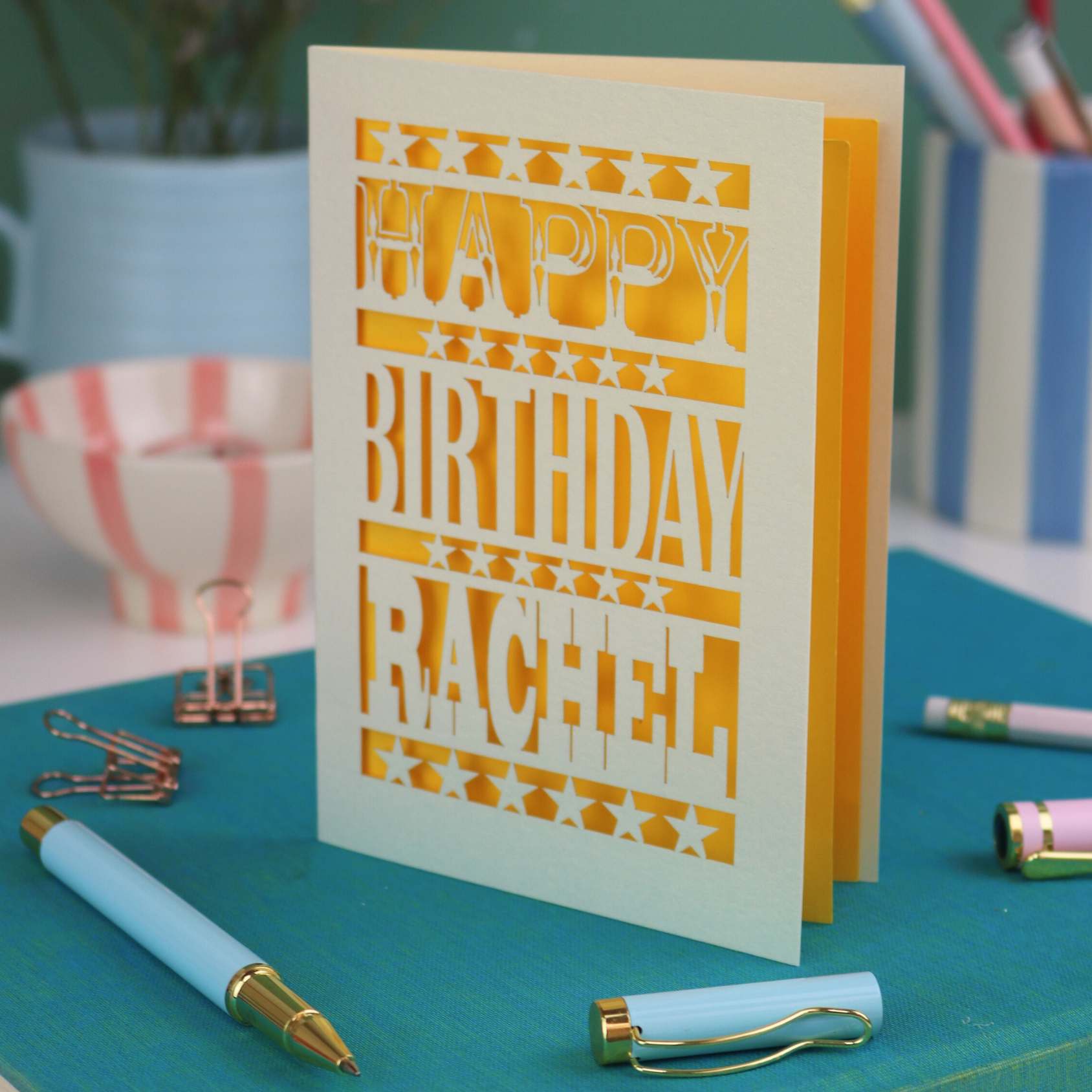 A laser cut personalised birthday card that says "Happy Birthday Rachel" in bold text with star design.