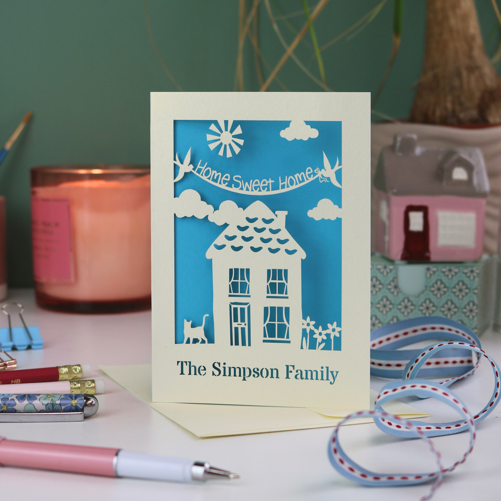 A laser cut new home card with cut out house design and the words "home sweet home" and personalised with the name of the recipients underneath