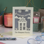A laser cut new home card with cut out house design and the words "home sweet home" and personalised with the name of the recipients underneath