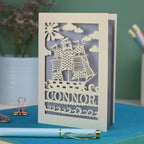 A personalised laser cut birthday card with cut out pirate ship illustration and the name Alfie 