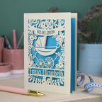 A personalised new baby card with laser cut floral vintage pram design. The baby's date of birth is cut out in stencil lettering in a banner, and the baby's name is at the bottom of the card.