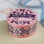 Pink washi tape roll with decorative design on a textured surface