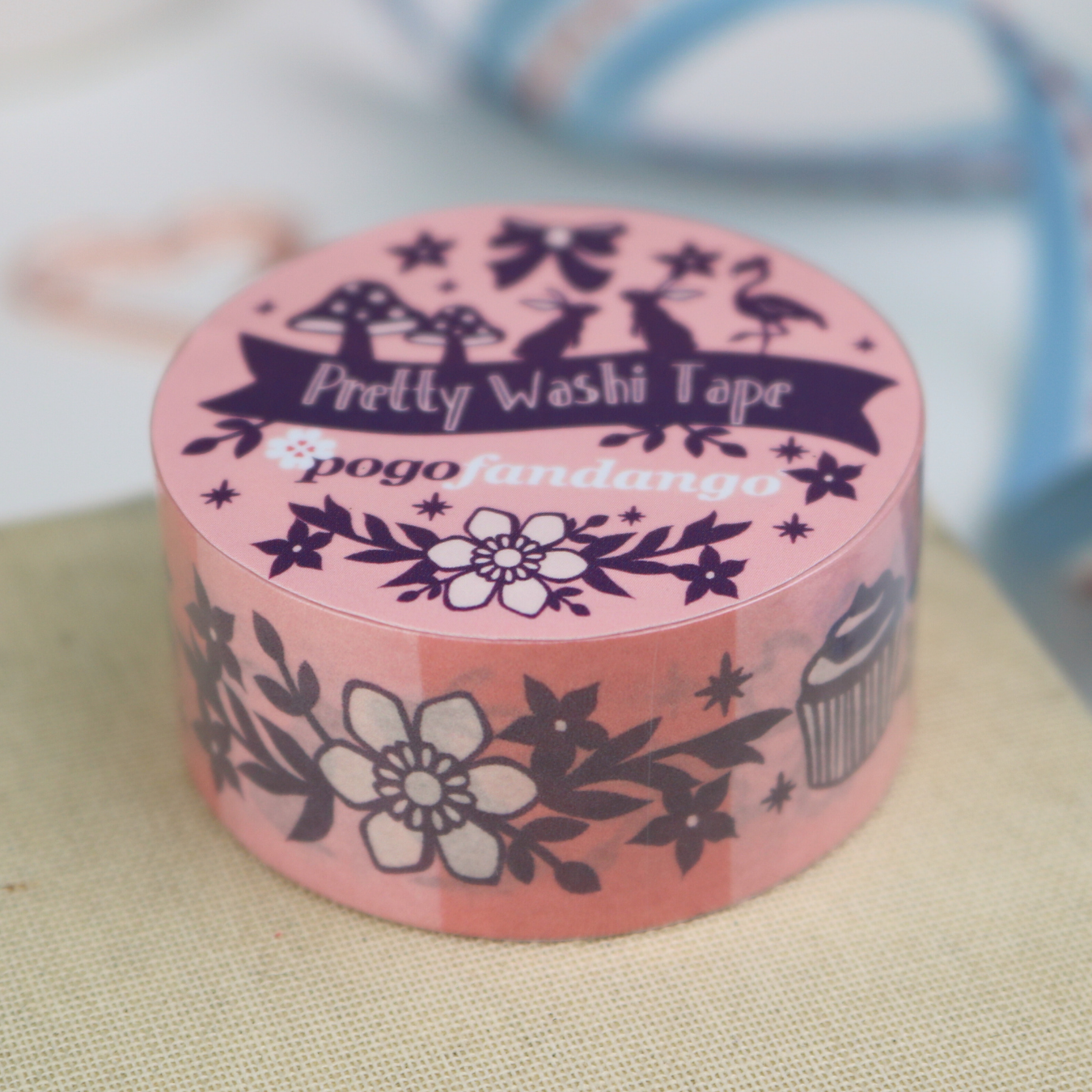 Pink washi tape roll with decorative design on a textured surface