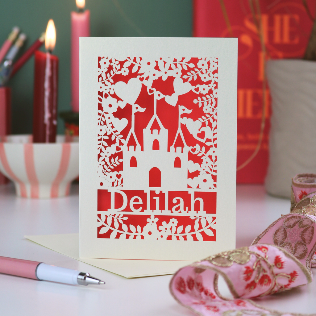Birthday Card with cut-out design and 'Delilah' text on a decorative background with candles and ribbons.