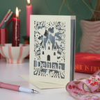Decorative girl's birthday card with laser-cut design on a table with candles and stationery.