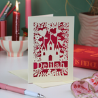 Decorative greetings card with castle design and 'Delilah' text on a table with candles and books.