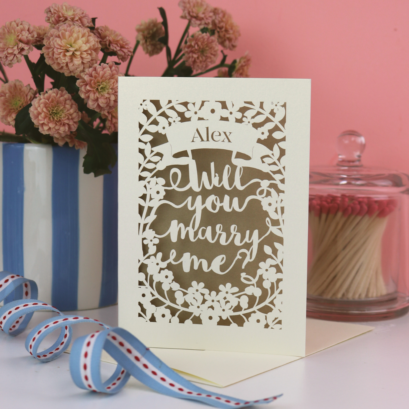 A laser cut card that says "Alex, will you marry me?" 