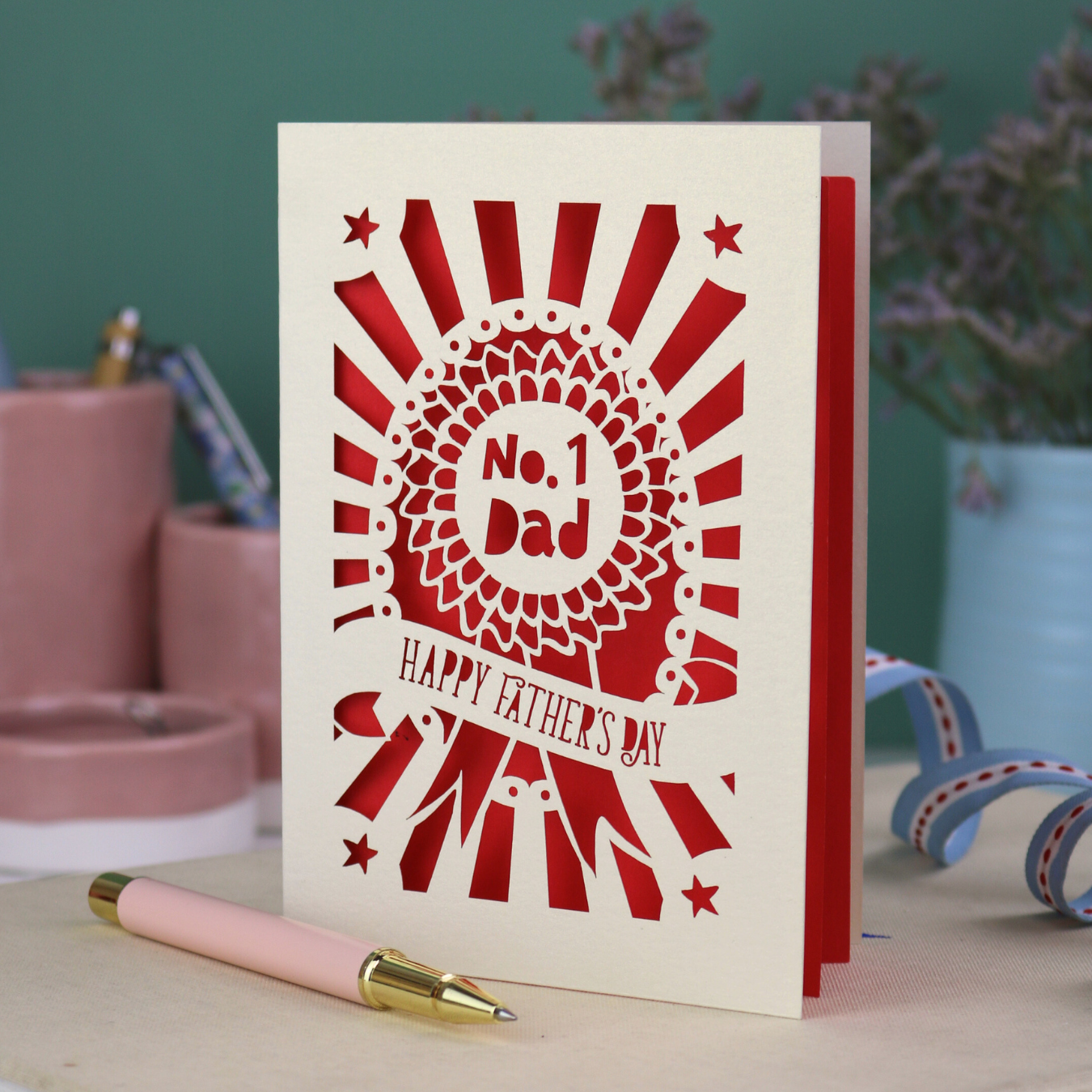 A laser cut cream Father's Day card with cut out rosette design and "No. 1 Dad" in the centre, and a banner with "Happy Father's Day" underneath. 