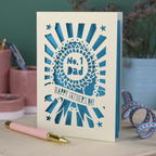 A laser cut cream Father's Day card with cut out rosette design and "No. 1 Dad" in the centre, and a banner with "Happy Father's Day" underneath. 