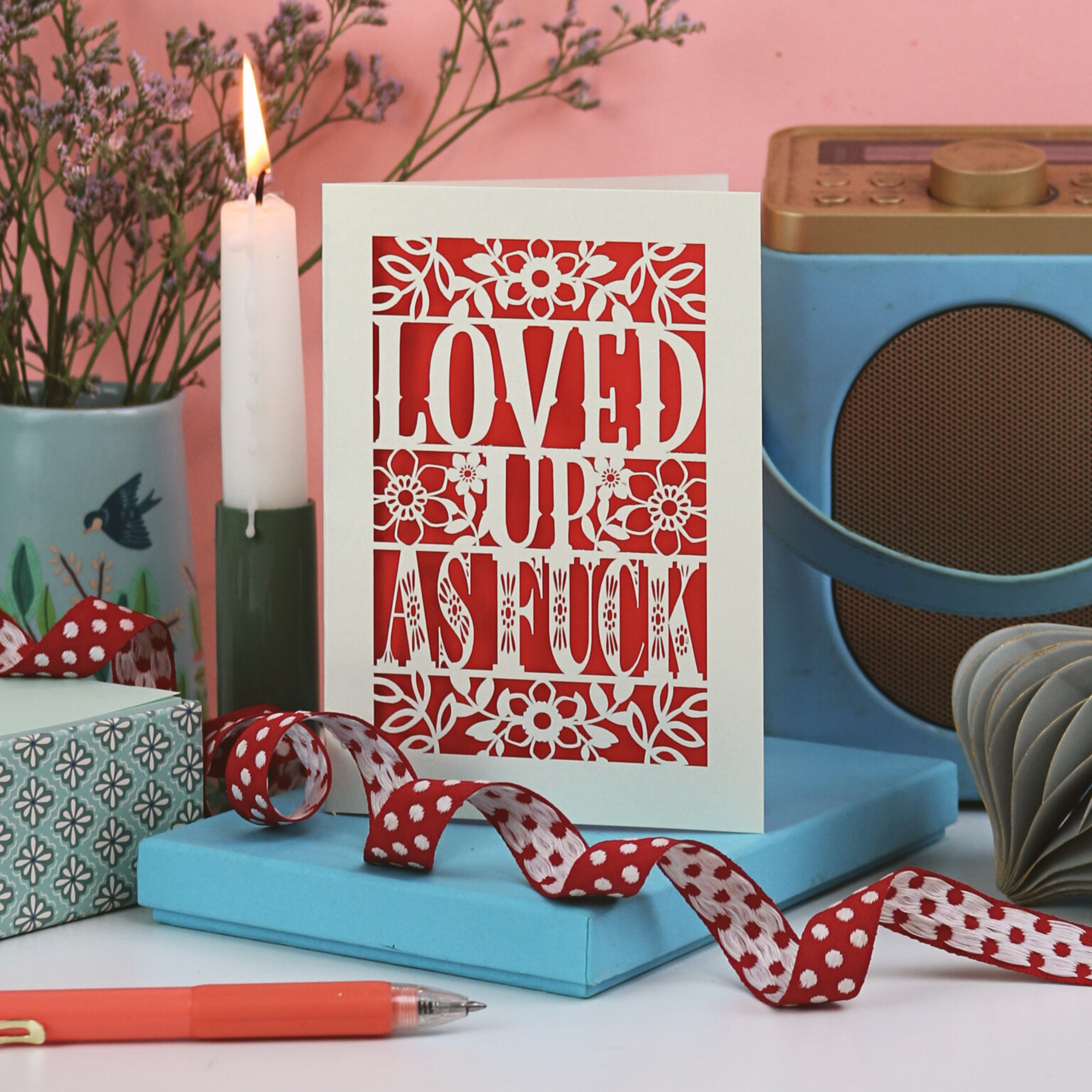Rude Valentine's Card with decorative text on a table with a candle, plant, and radio in the background