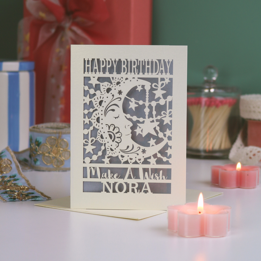 Laser-cut birthday card with decorative elements on a table with candles and gifts.