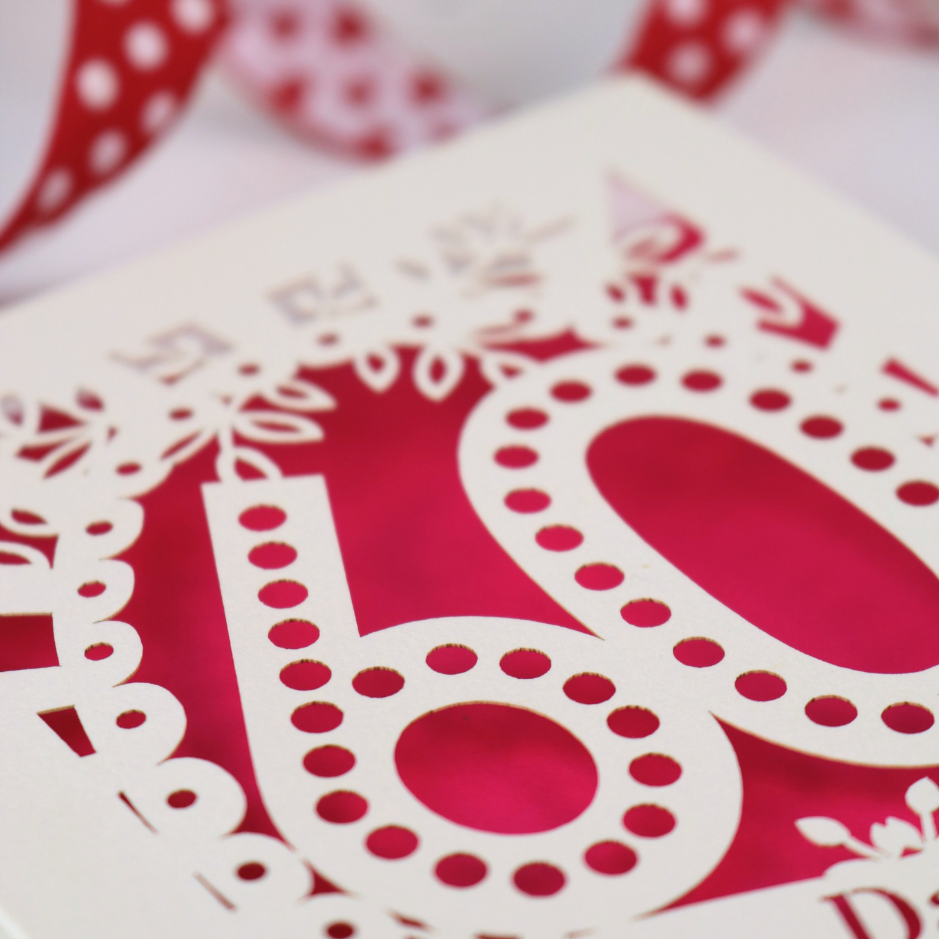 A paper cut out 60th birthday card close up with cream card and shocking pink paper insert