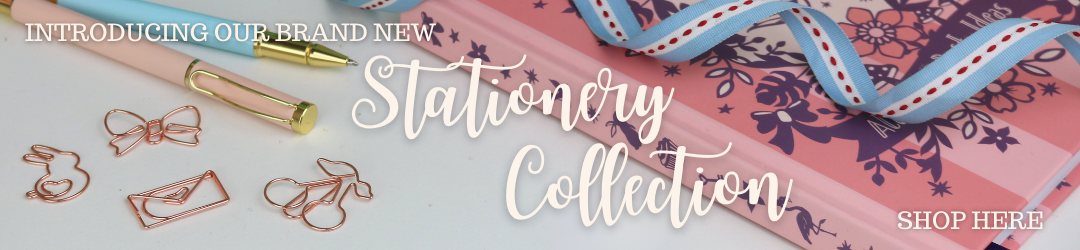 A photo of the new whimsical stationery collection notebook, pens and paperclips on a white surface with the text "Introducing our brand new stationery collection. Shop here"