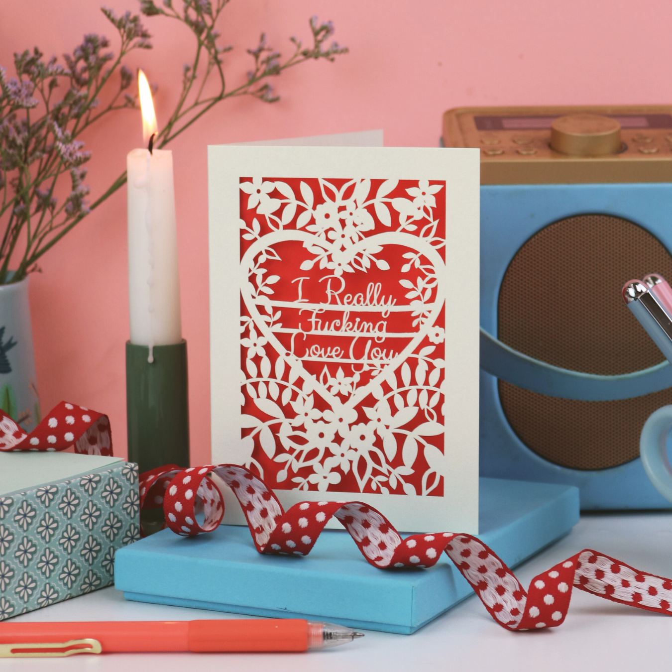 Rude Valentine's Card with laser cut decorative text, 'I really fucking love you', and heart design on a table with a candle and decorative items.