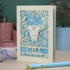 Personalised laser cut Birthday card with zodiac design featuring a bull on a pink background, with a pen and decorative ribbon in the foreground.