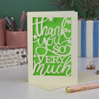 A laser cut Thank You card with handwritten cut out text that says "Thank you so very much", with an green paper insert. 