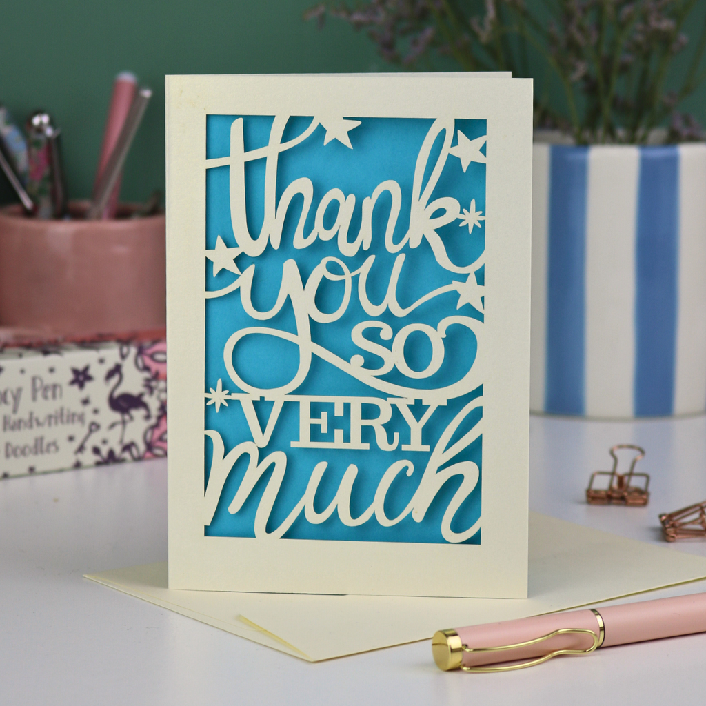 A laser cut Thank You card with handwritten cut out text that says "Thank you so very much", with a blue paper insert. 