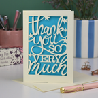 A laser cut Thank You card with handwritten cut out text that says "Thank you so very much", with a blue paper insert. 