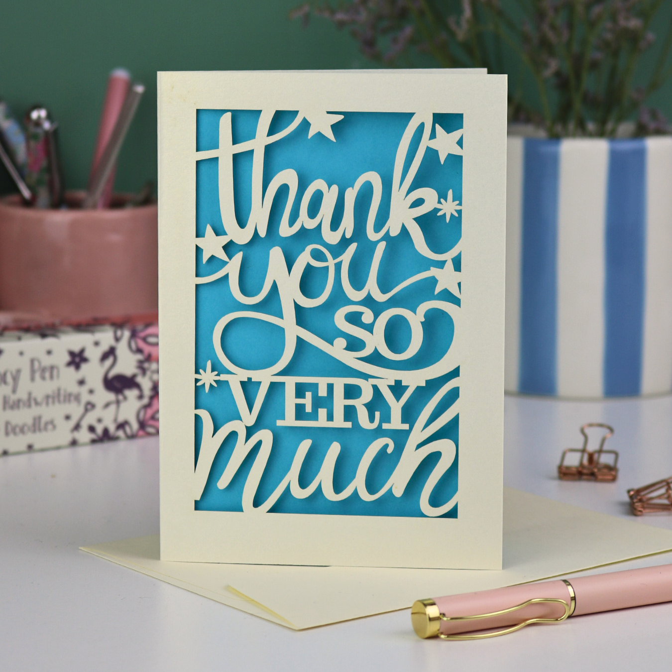 A laser cut Thank You card with handwritten cut out text that says "Thank you so very much", with a blue paper insert. 