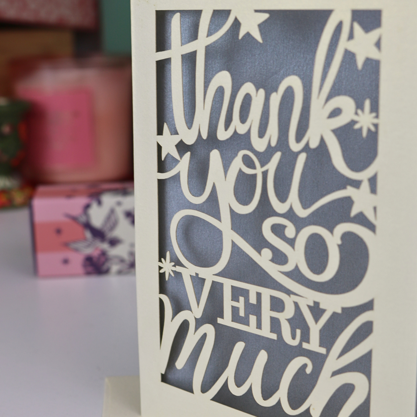 A laser cut Thank You card with handwritten cut out text that says "Thank you so very much", with a silver paper insert. 
