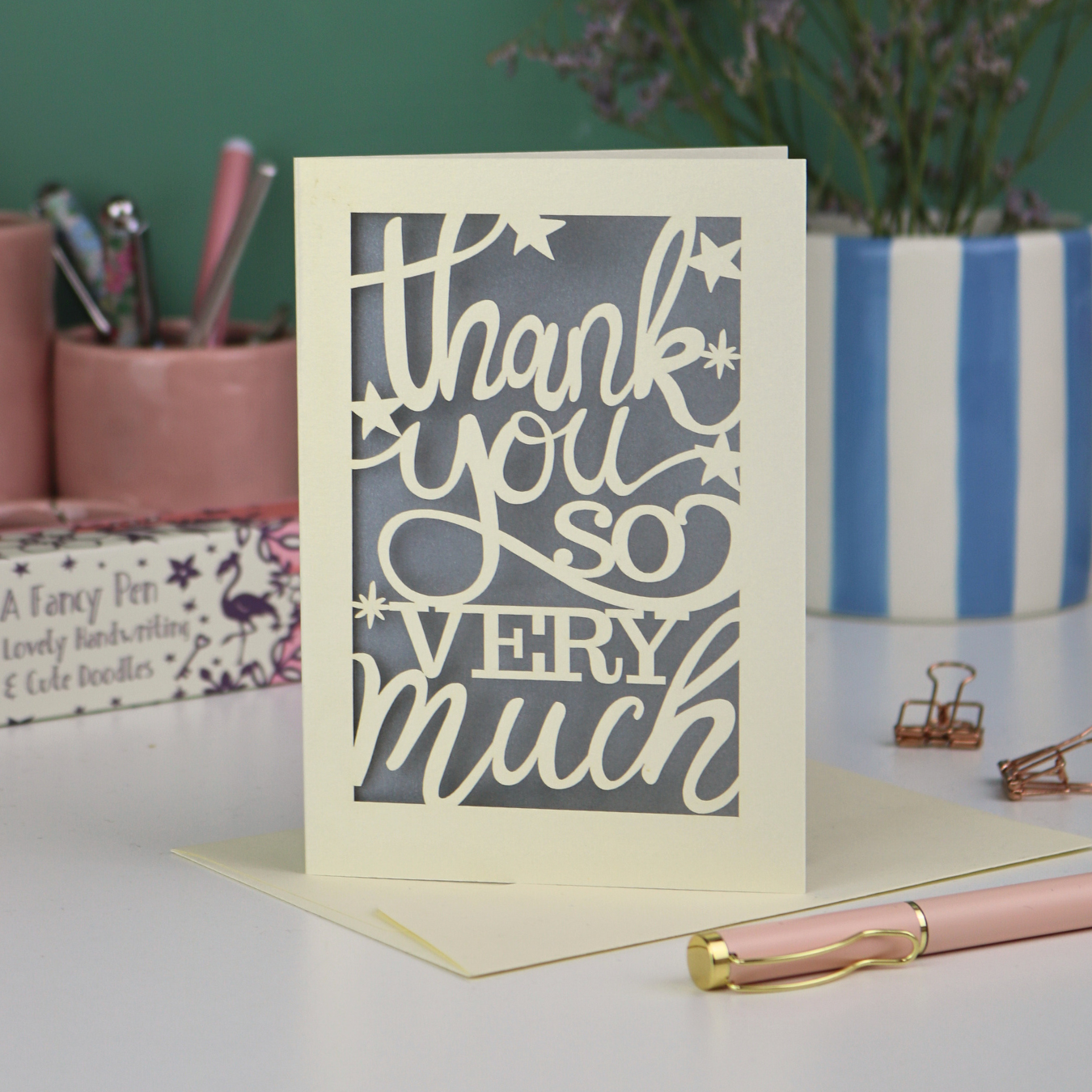 A laser cut Thank You card with handwritten cut out text that says "Thank you so very much", with a silver paper insert. 