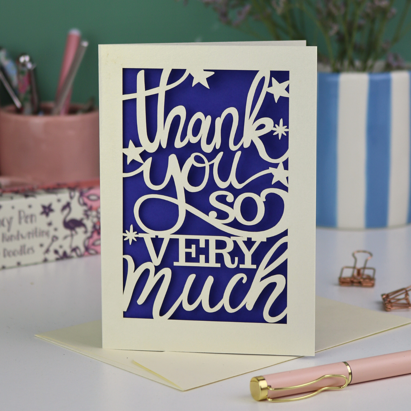 A laser cut Thank You card with handwritten cut out text that says "Thank you so very much", with a violet paper insert. 