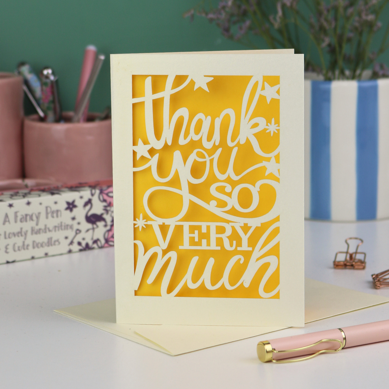 A laser cut Thank You card with handwritten cut out text that says "Thank you so very much", with a yellow paper insert. 