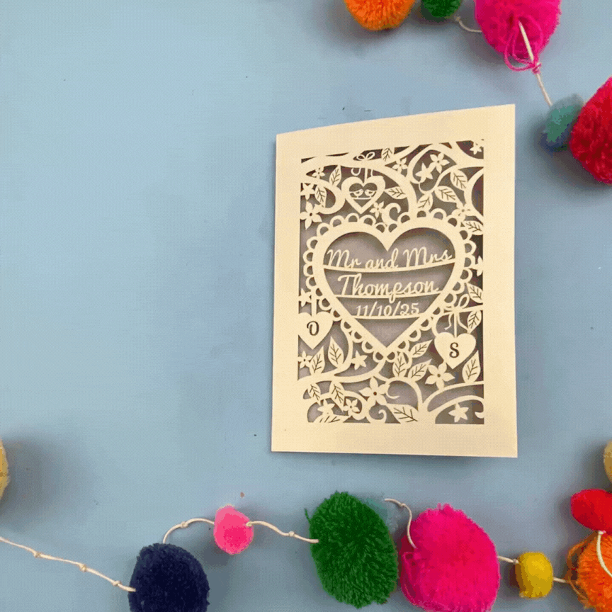 Decorative wedding anniversary card with personalized text on a blue background with colourful pom-poms and paper clips.