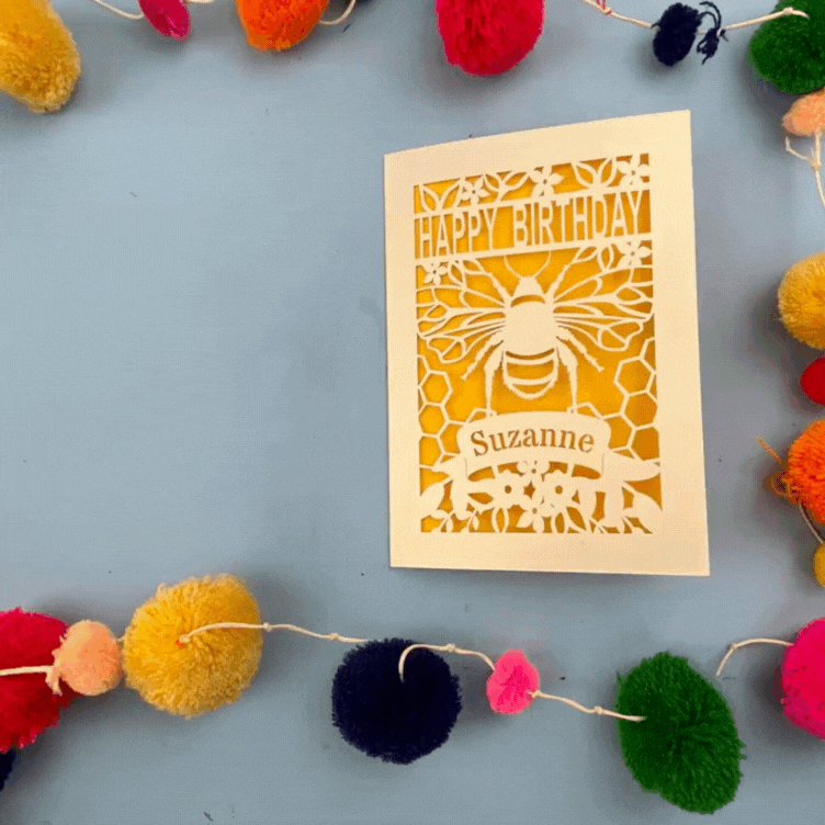 Birthday card with bee design and colourful pom-poms on a blue background