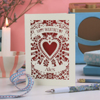 Personalised Valentine's Day card with a laser cut heart design on a table with decorative items.