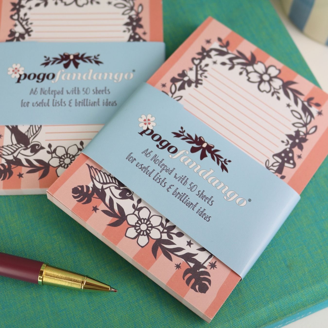 Small notebooks with floral designs and 'pogofandango' branding on a green surface.