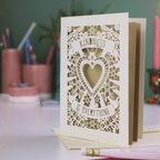 Laser-cut thank you card with decorative design and text, "Kindness is everything" on a desk with stationery items.