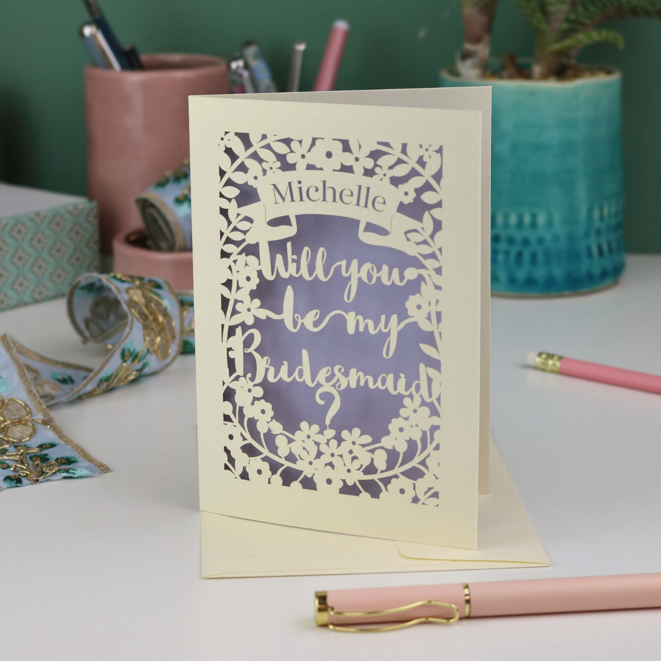 Personalised Laser cut Card with 'Will you be my Bridesmaid?' text on a desk with stationery items.