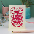 Laser cut Card with 'Will you be my Bridesmaid?' text on a desk with stationery items.